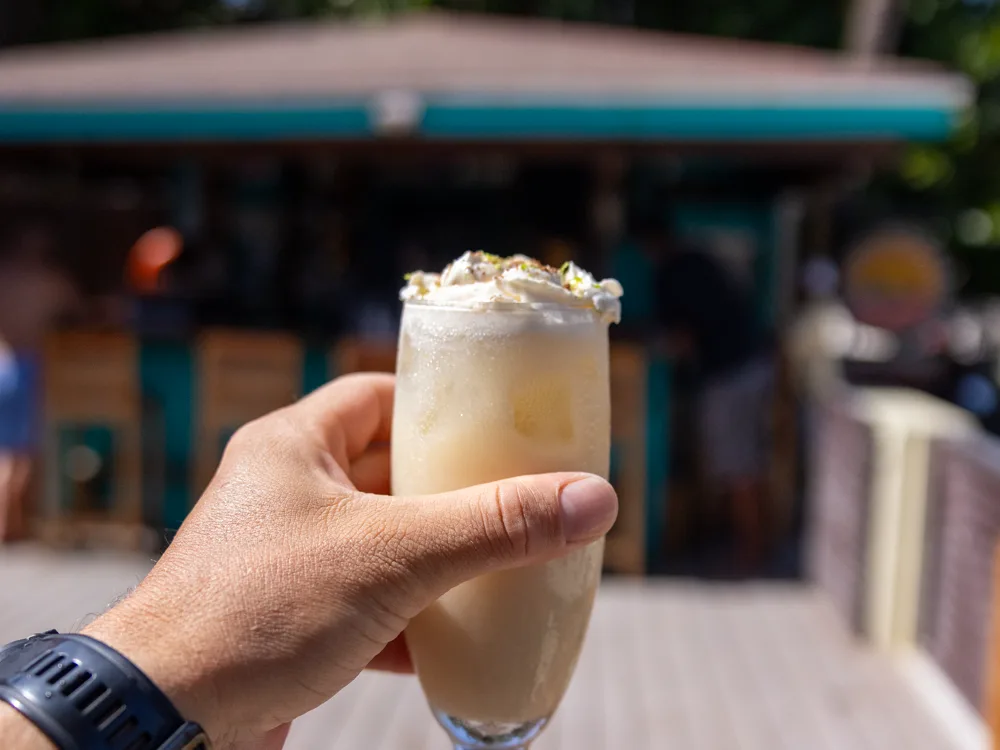 A blended cocktail held up in front of the Lazy Pelican bar