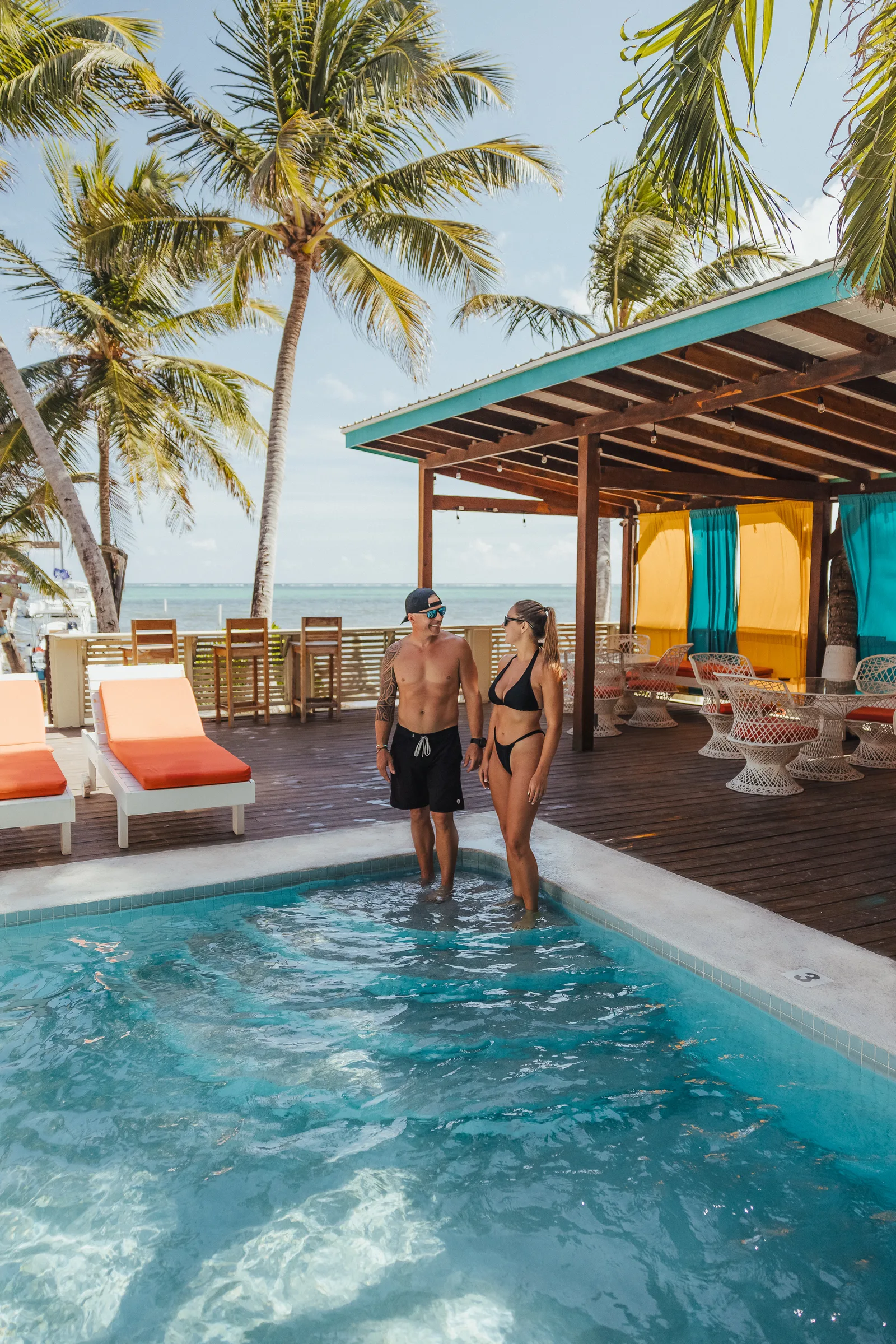 Couple stepping into the pool by the cabanas at Ocean Tide Beach Resort, San Pedro Belize