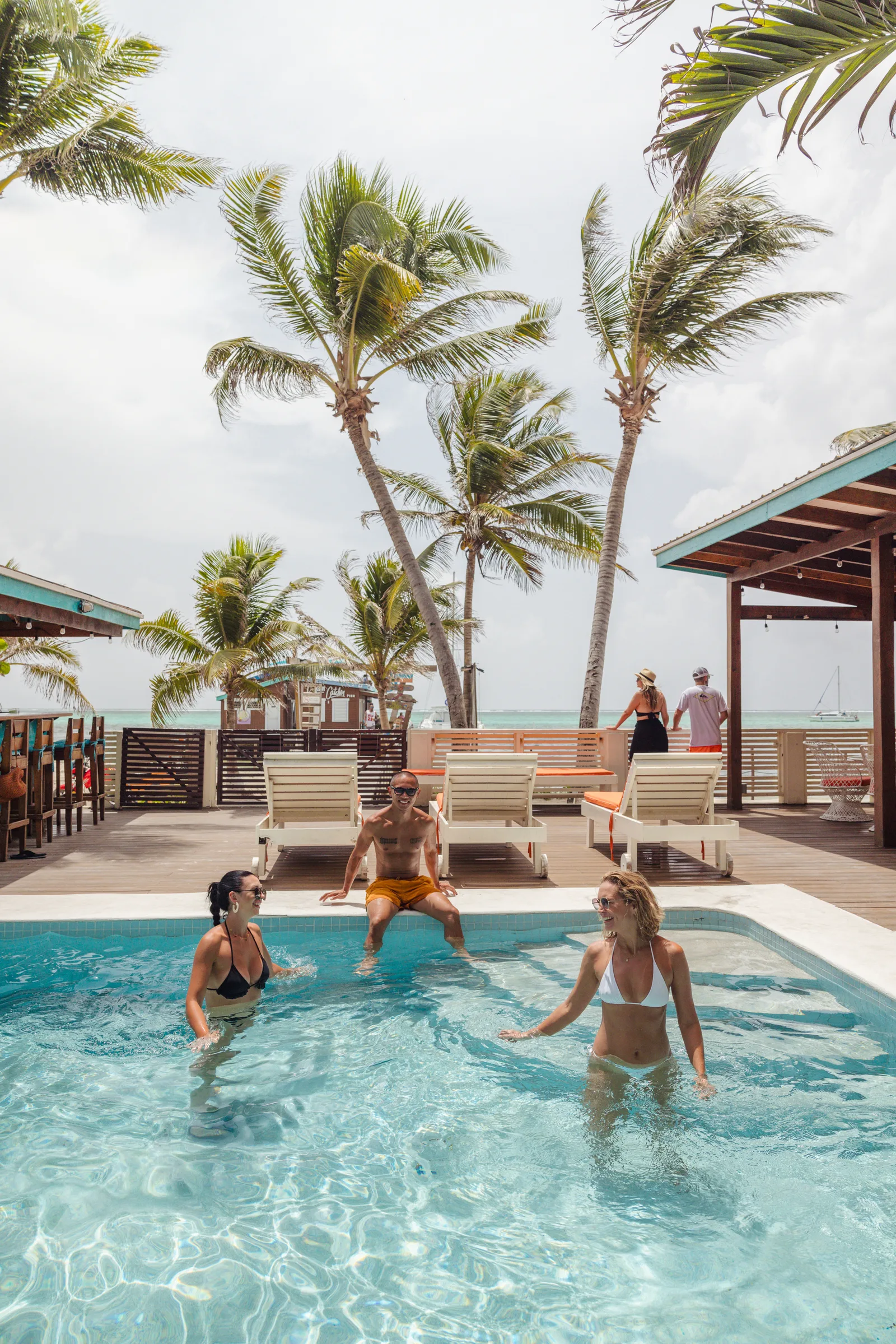 Guests in the pool on the deck at Ocean Tide Beach Resort, with the Caribbean beyond: San Pedro Belize