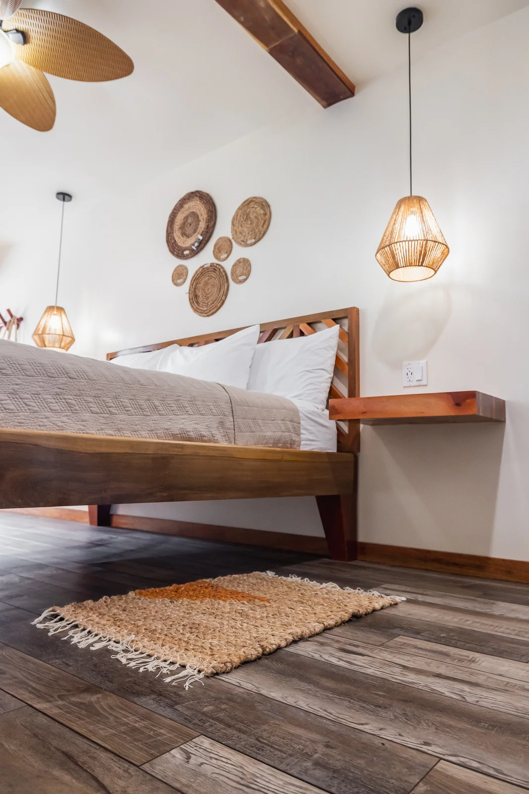Handcrafted hardwood bed, woven pendant lights and Belizean jute rug in an Ocean Tide room